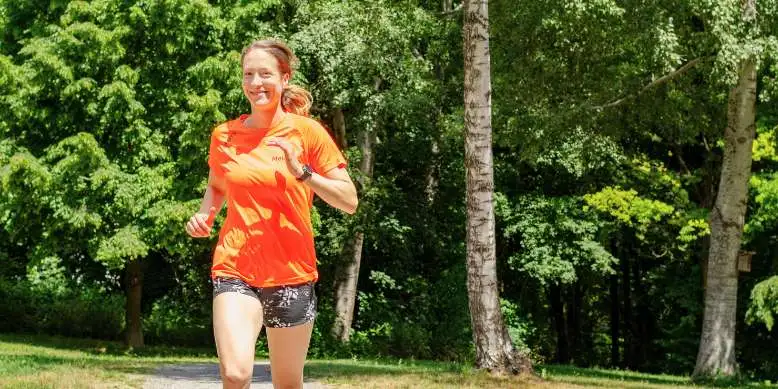 Frau mit orangem T-Shirt im Park beim Joggen