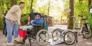 Junger Freiwilliger ist mit Rollstuhlfahrer unterwegs zum Biergarten