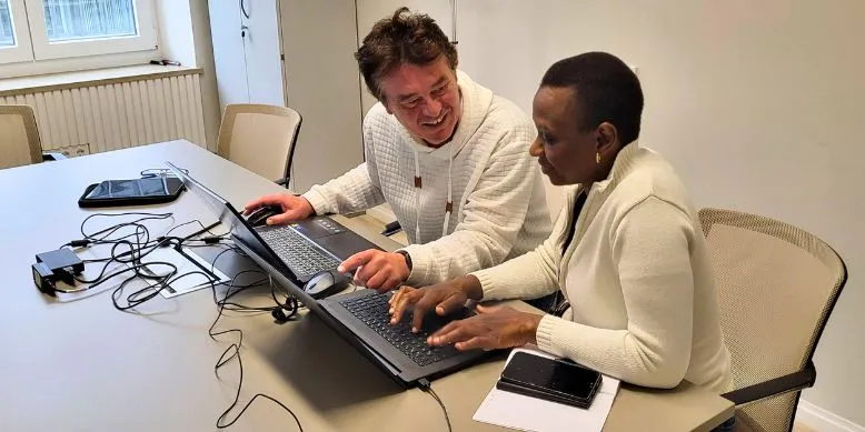 Jobmentor Rafael unterstützt eine Frau am Laptop